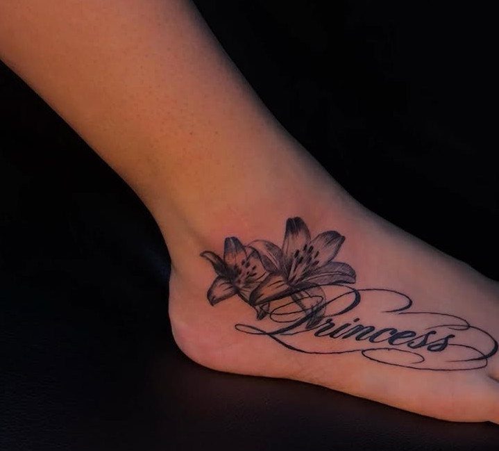 Ankle tattoo featuring two lilies and the word Princess in cursive black ink.