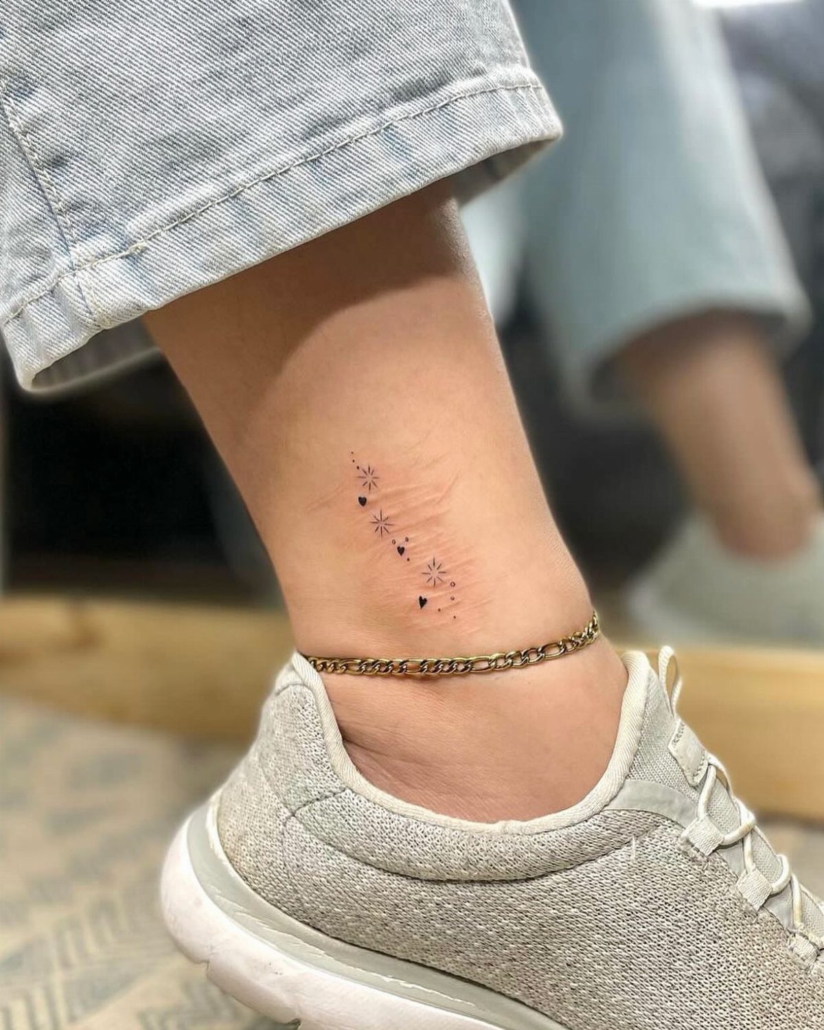 Ankle tattoo of small stars and dots camouflaging a scar on a person.