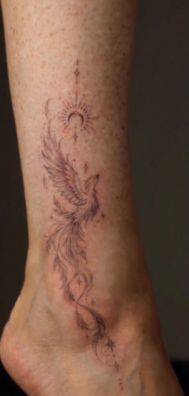 Phoenix bird tattoo on an ankle with a crescent moon and stars above it.