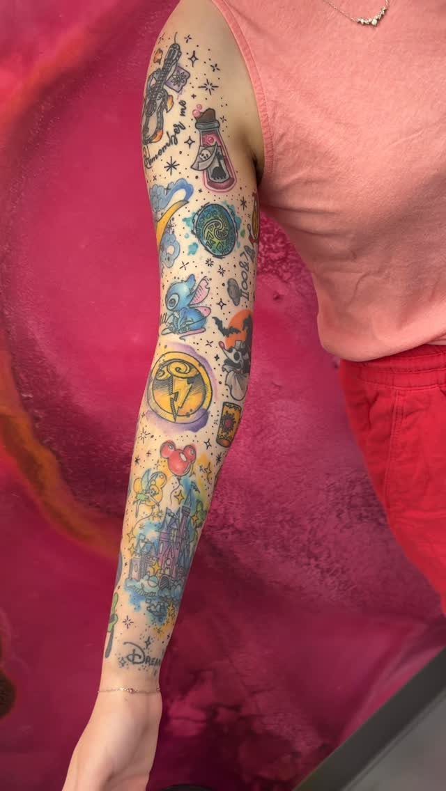 Full sleeve tattoo on an arm featuring colorful Disney characters and a castle.