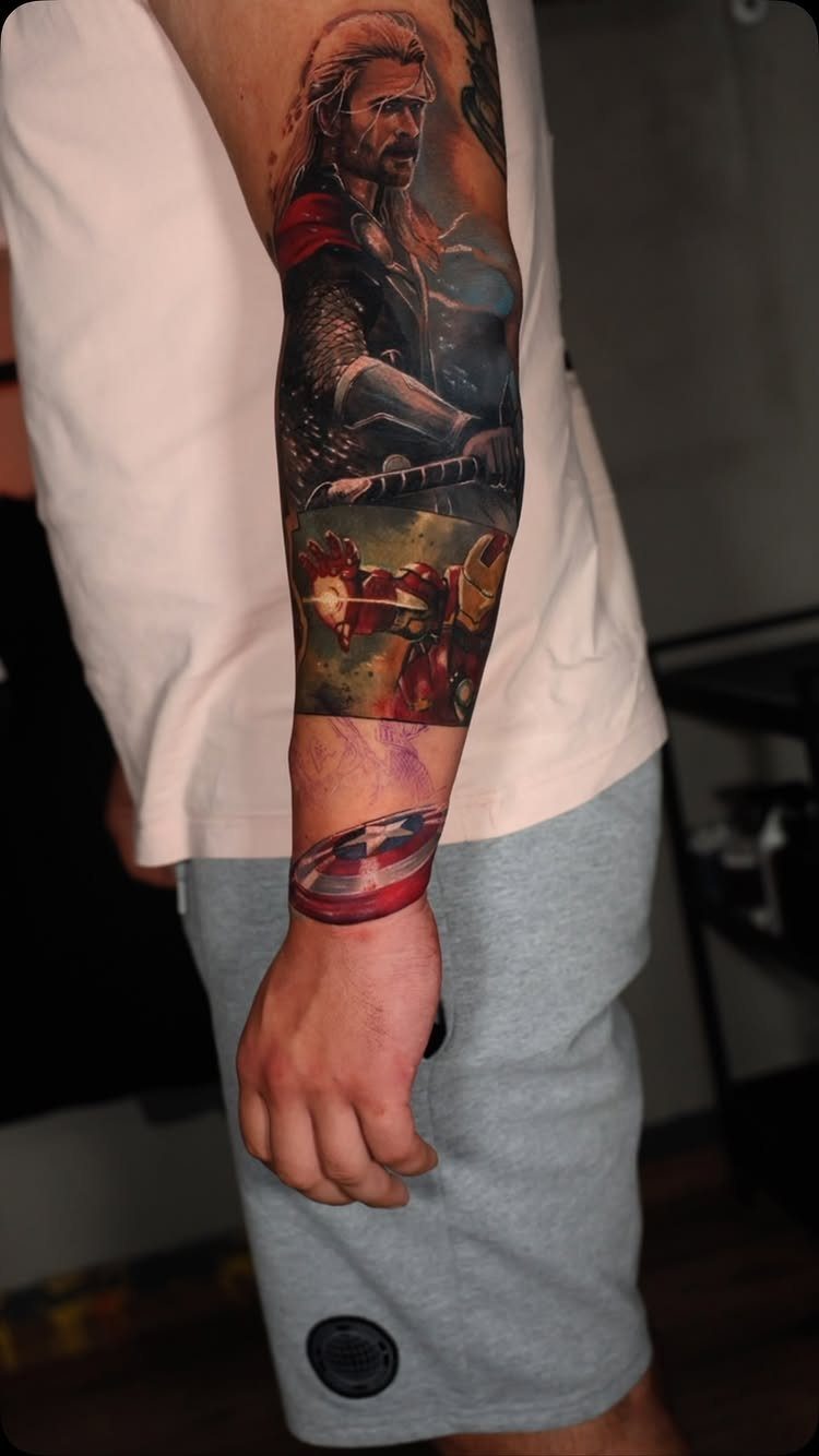 Full sleeve tattoo on an arm featuring Thor, Iron Man, and Captain America's shield.