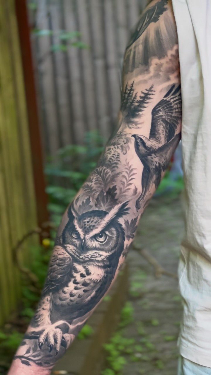Detailed black and gray nature sleeve tattoo featuring an owl and flying hawk.