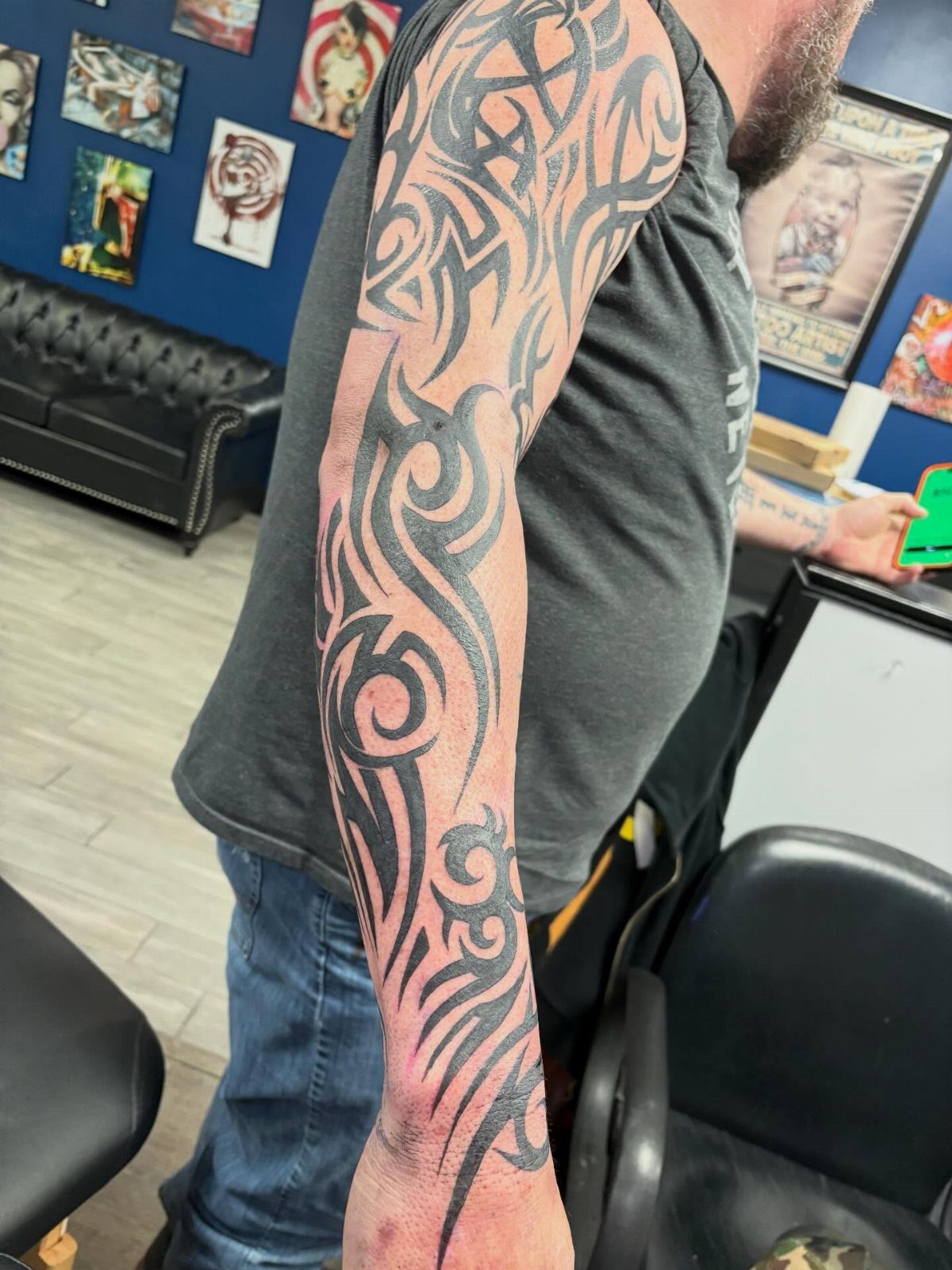 Tribal sleeve tattoo with bold black swirling patterns covering a man's entire arm.