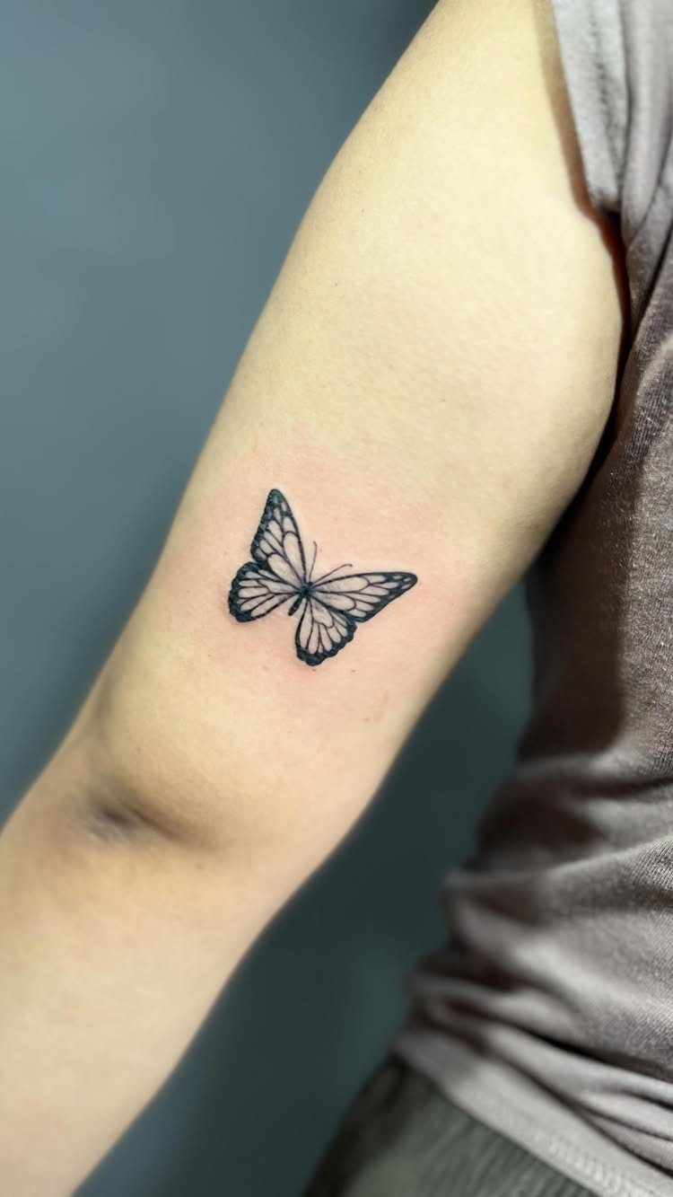 Butterfly tattoo on the back of a person's upper arm.