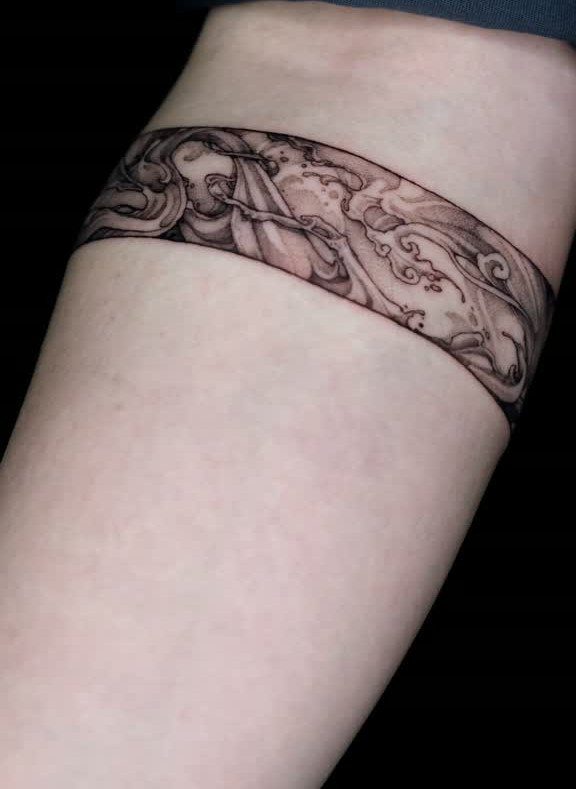 Ocean wave tattoo wrapped around the back of a person's upper arm.