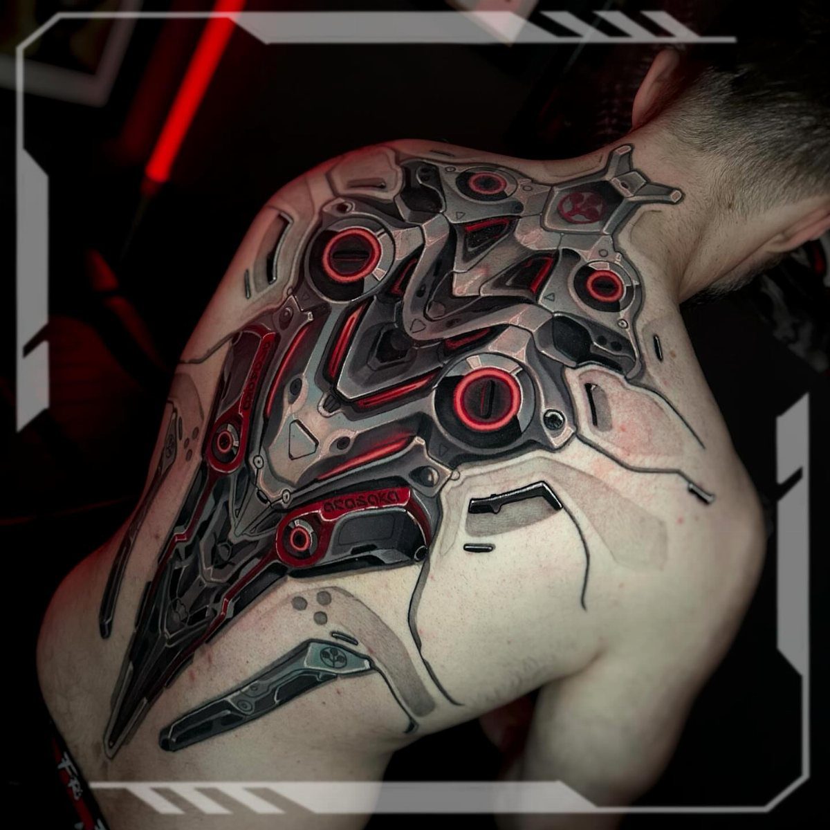 Biomechanical tattoo on a man's back with metallic grey and glowing red details