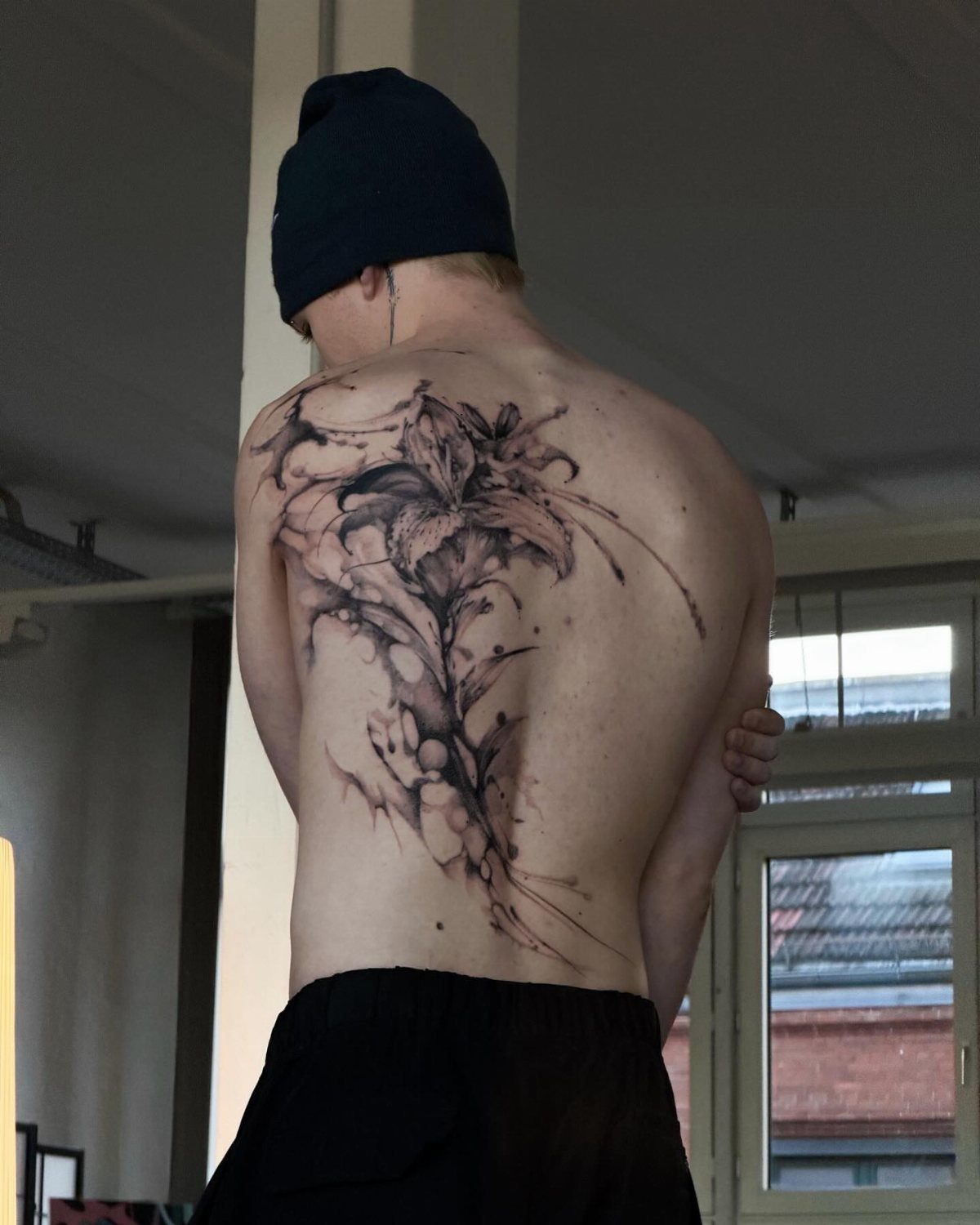 Man with a large black and grey flower tattoo covering his entire back