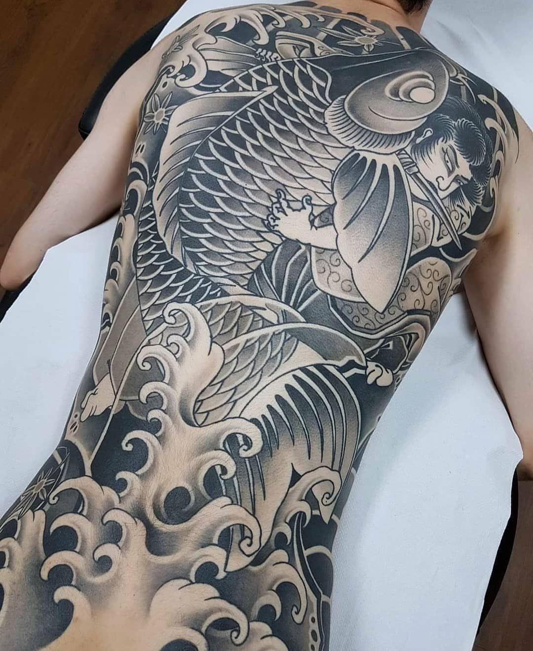 Large Japanese Irezumi koi fish and wave tattoo covering a man's full back