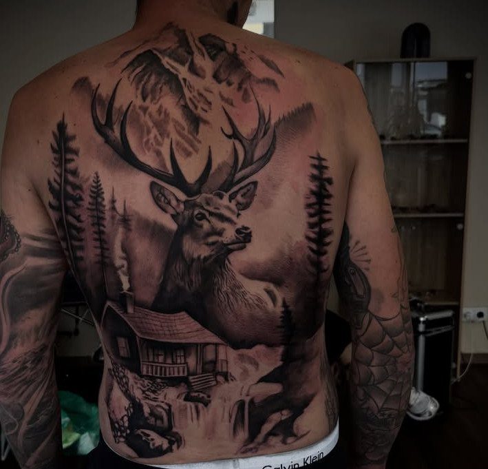 Stag and mountain landscape tattoo covering the full back of a man