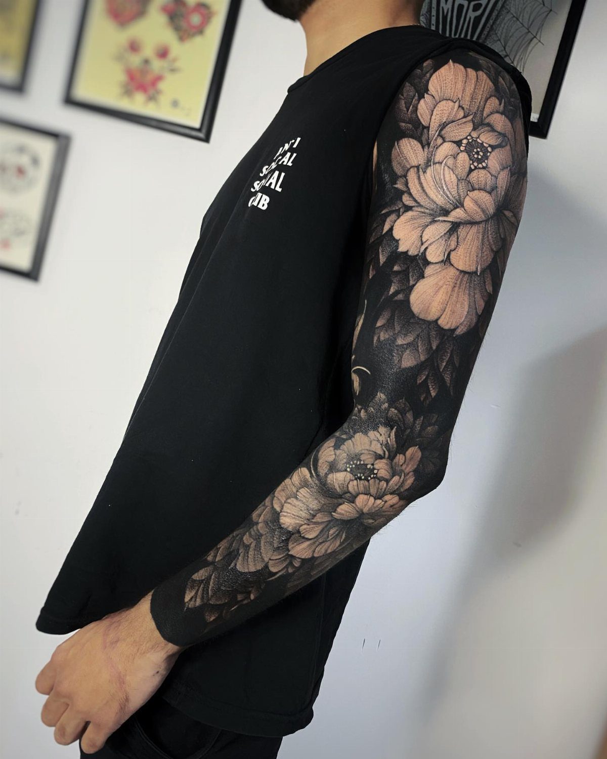 Full sleeve black and grey tattoo of peonies and clouds on a man's arm