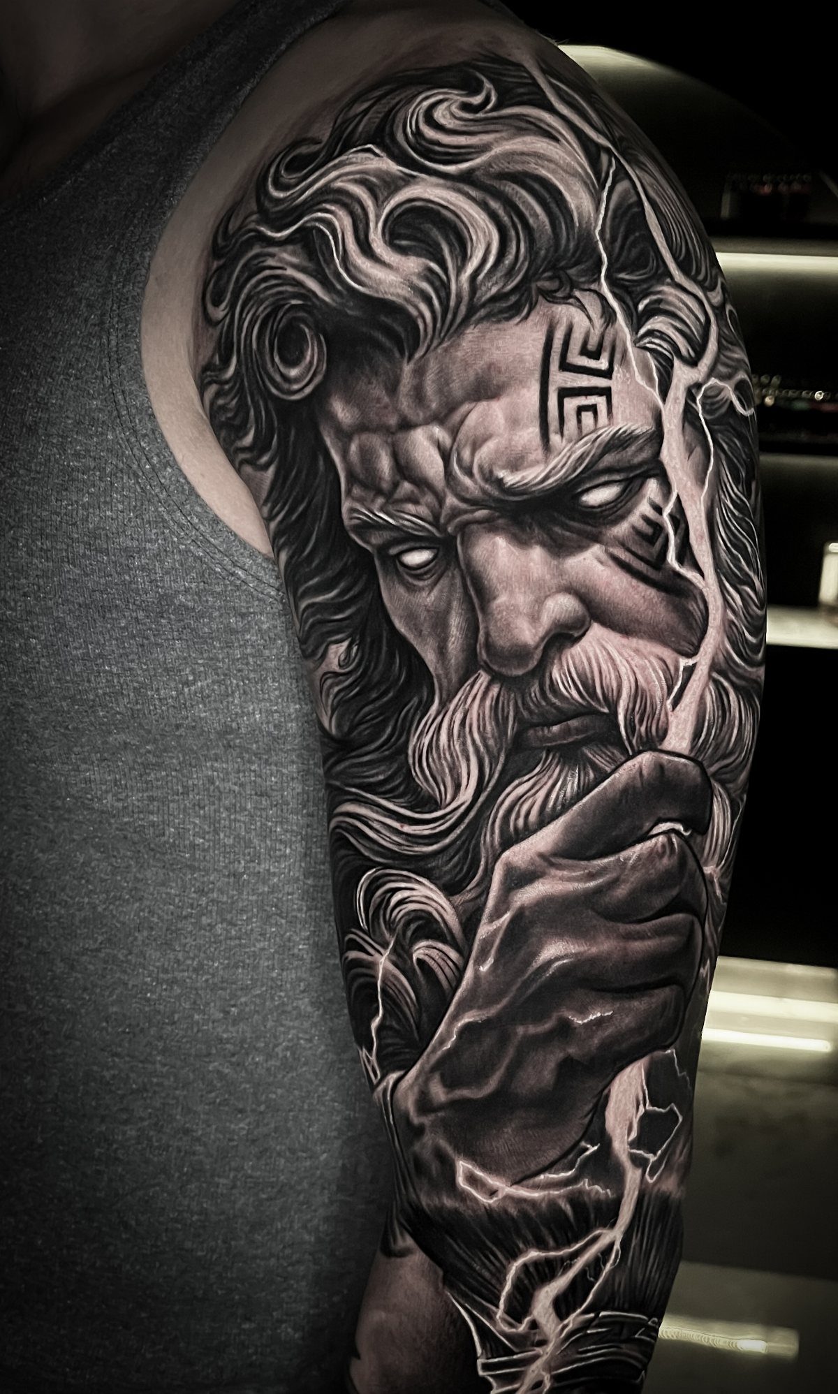 Greek god Zeus tattoo with lightning bolts on a man's muscular upper arm