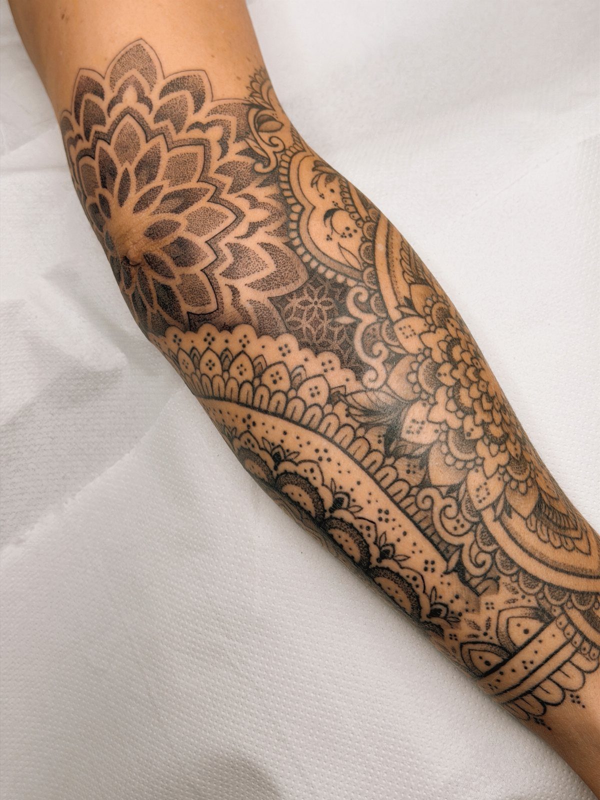 Ornamental mandala tattoo with intricate black ink patterns covering a person's arm.