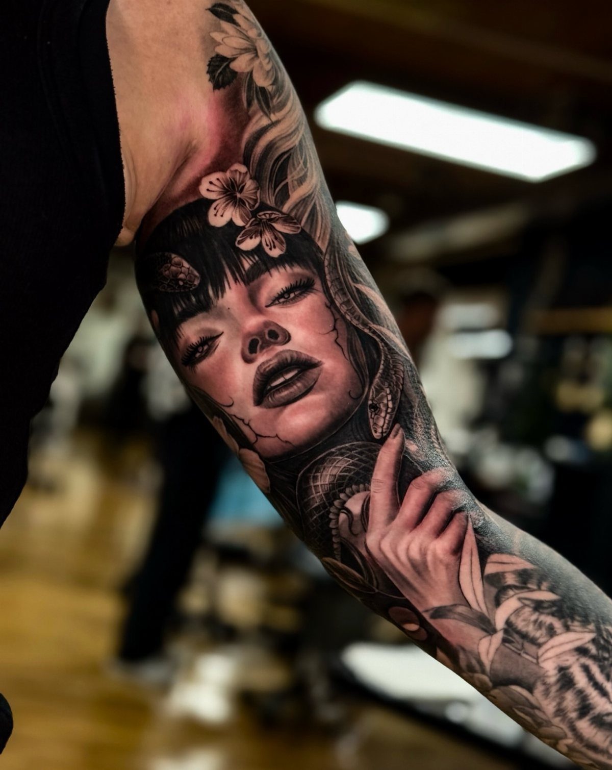 Detailed portrait tattoo of a woman with flowers and a snake on a bicep