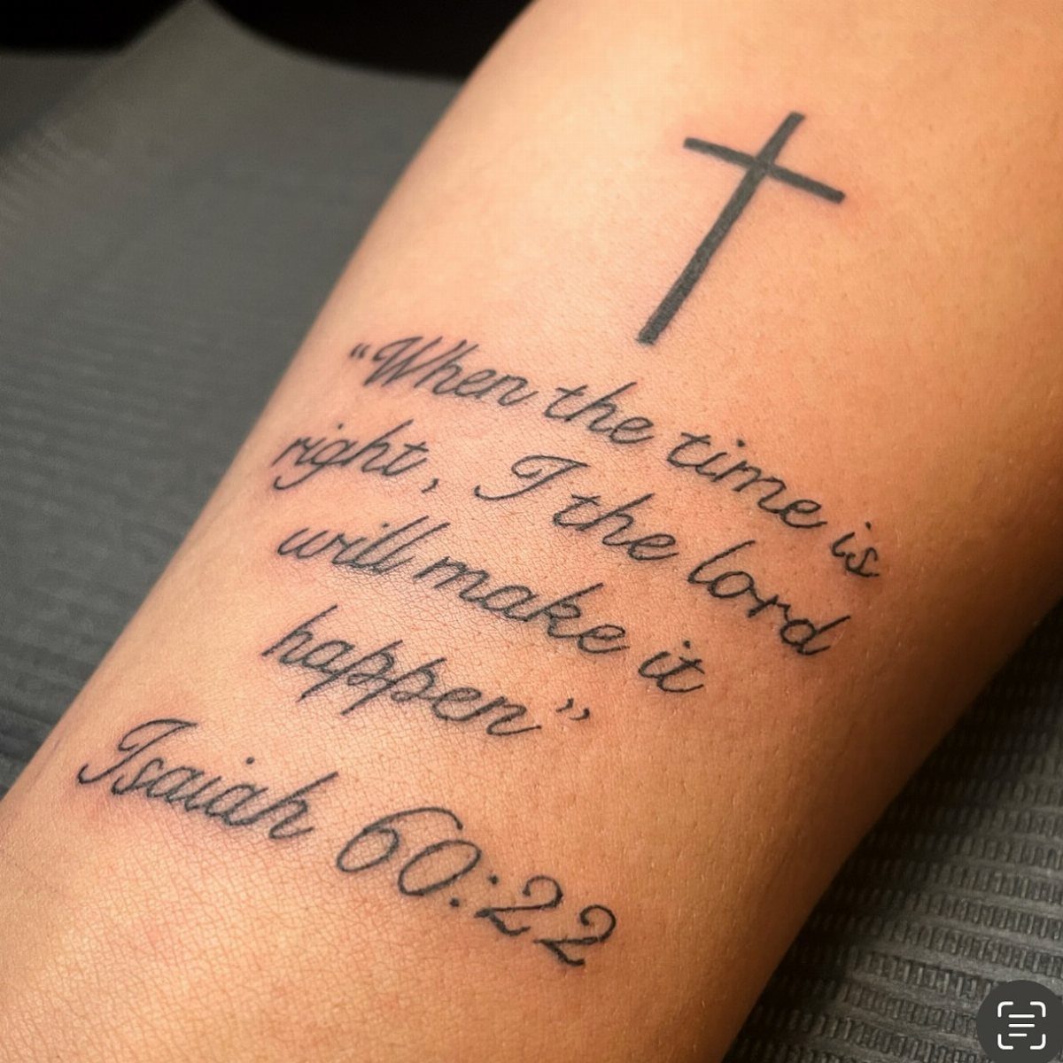Bicep tattoo featuring a Christian cross and a Bible verse from Isaiah 60:22