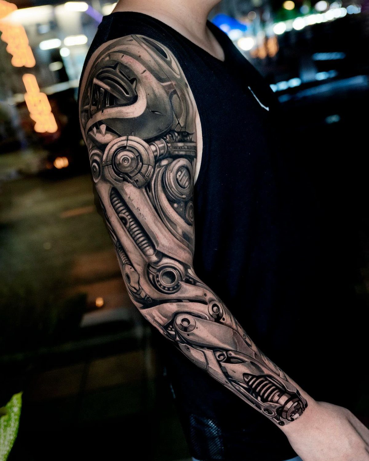 Biomechanical tattoo on a man's arm depicting intricate robotic parts and metallic machinery.