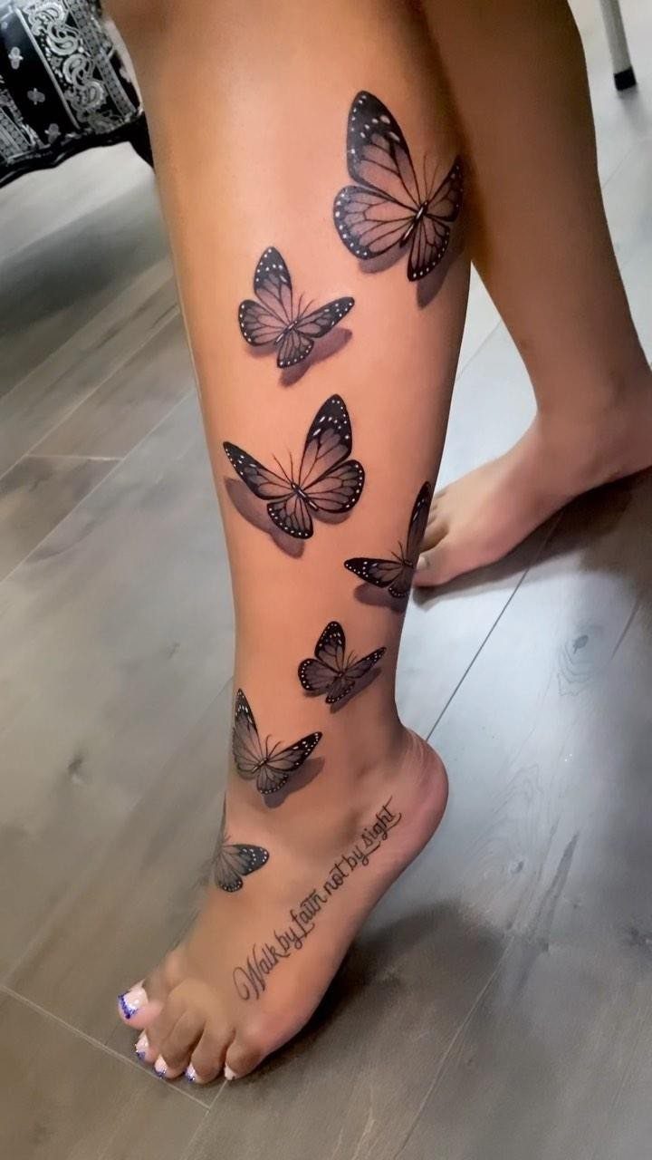 Butterfly tattoos ascending a woman's lower leg and foot on a wooden floor.