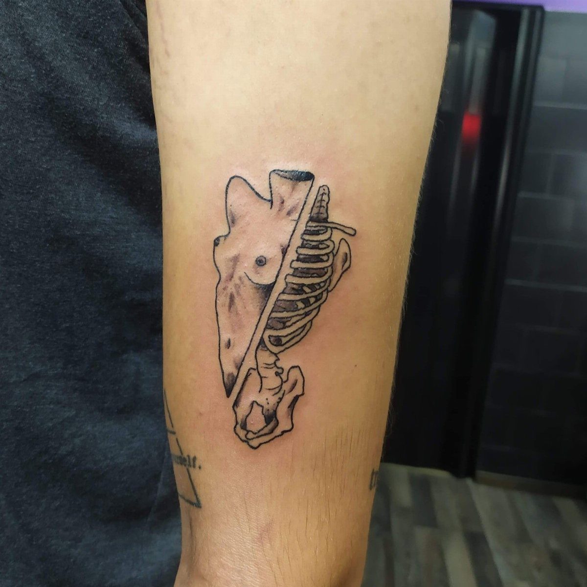 Forearm tattoo showing a split anatomical view of a human torso and ribcage.