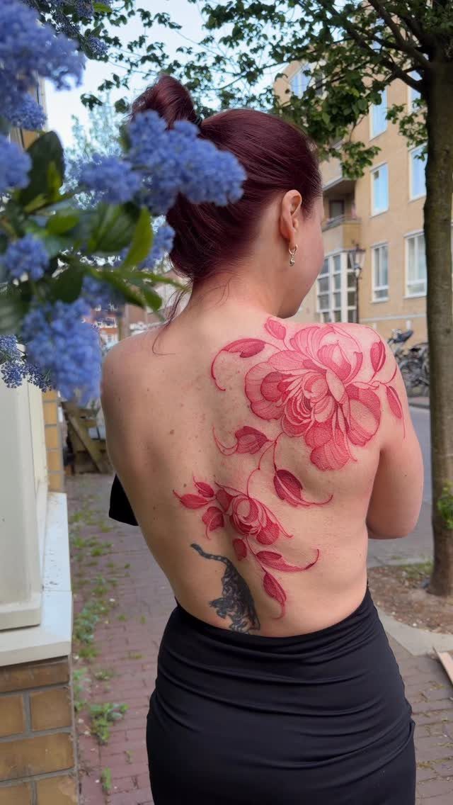 Woman with red hair showing a large red rose tattoo on her back.