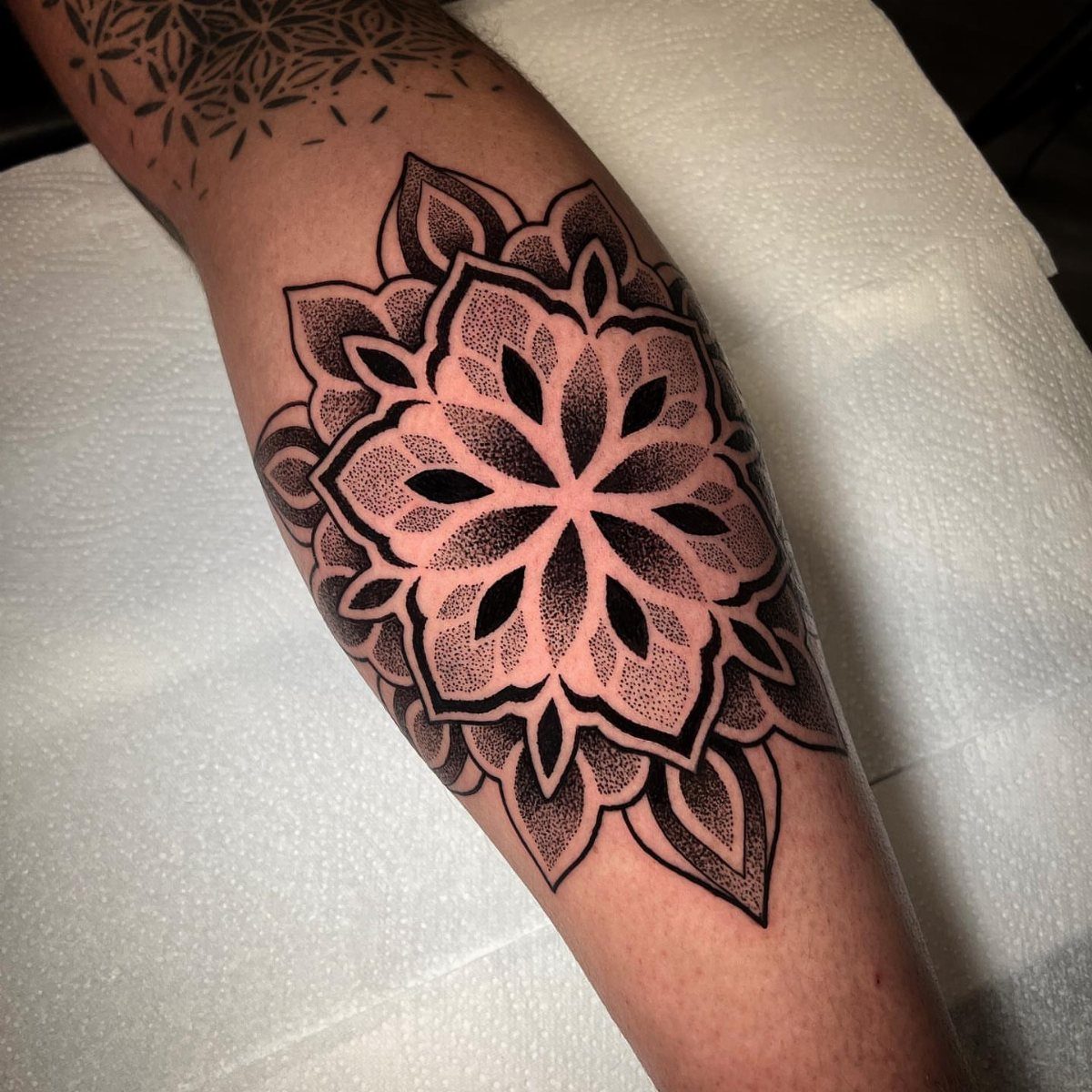 Mandala floral tattoo with dotwork shading on a person's lower leg calf