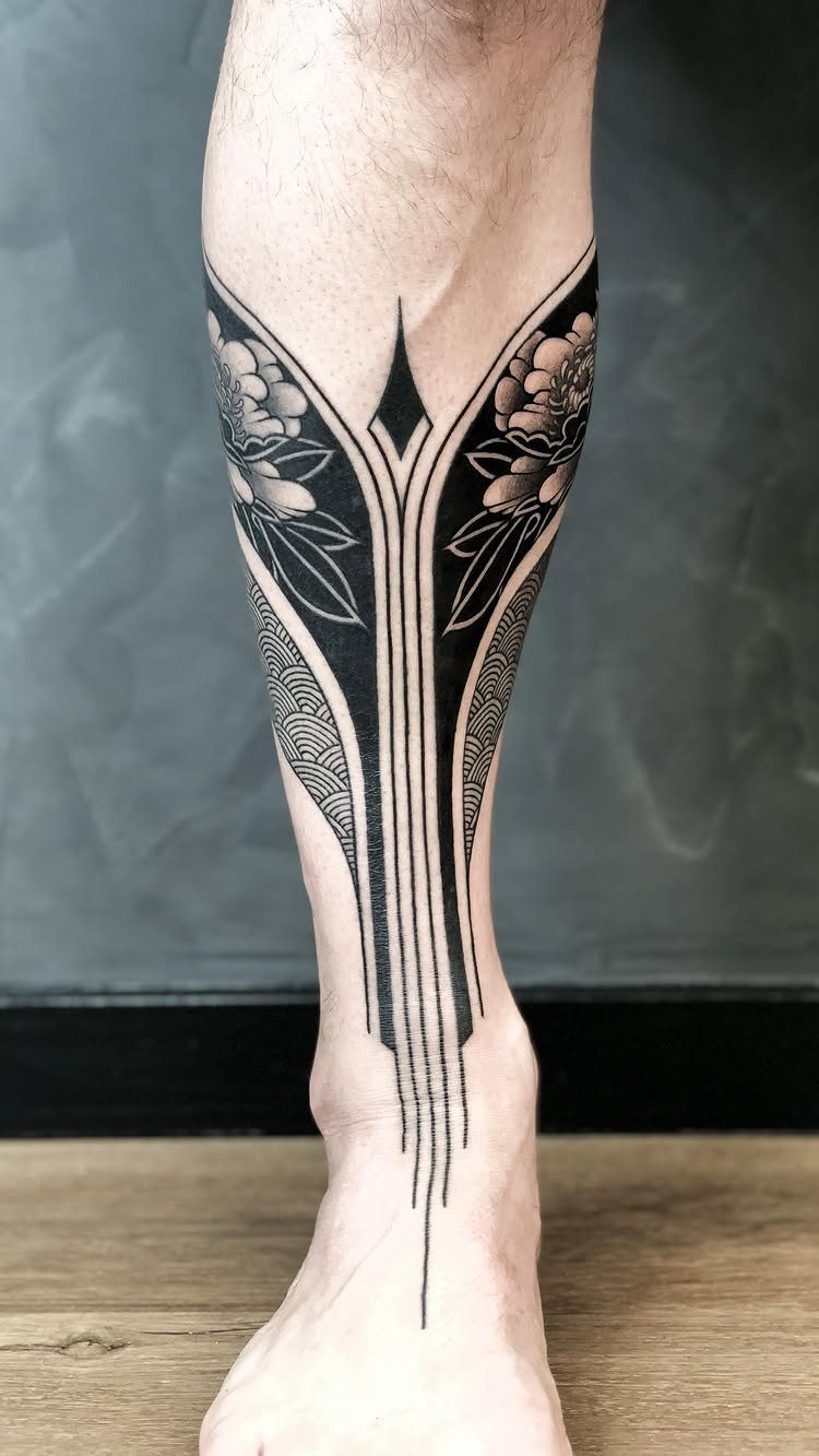 Geometric and floral black ink tattoo on a man's lower leg and ankle.