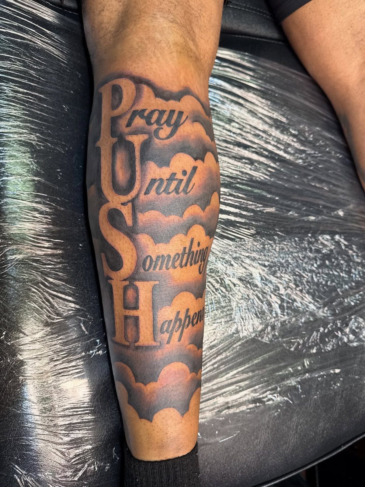 Calf tattoo with the motivational text Pray Until Something Happens and large PUSH letters.