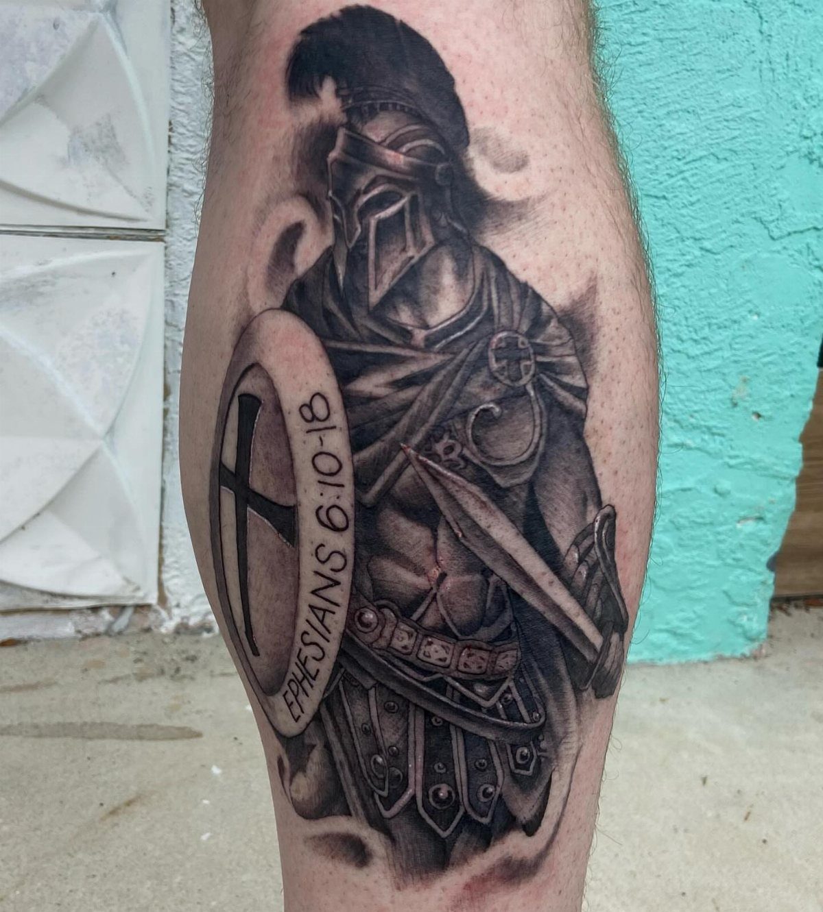 Roman warrior tattoo on a calf featuring a plumed helmet, shield, and sword.