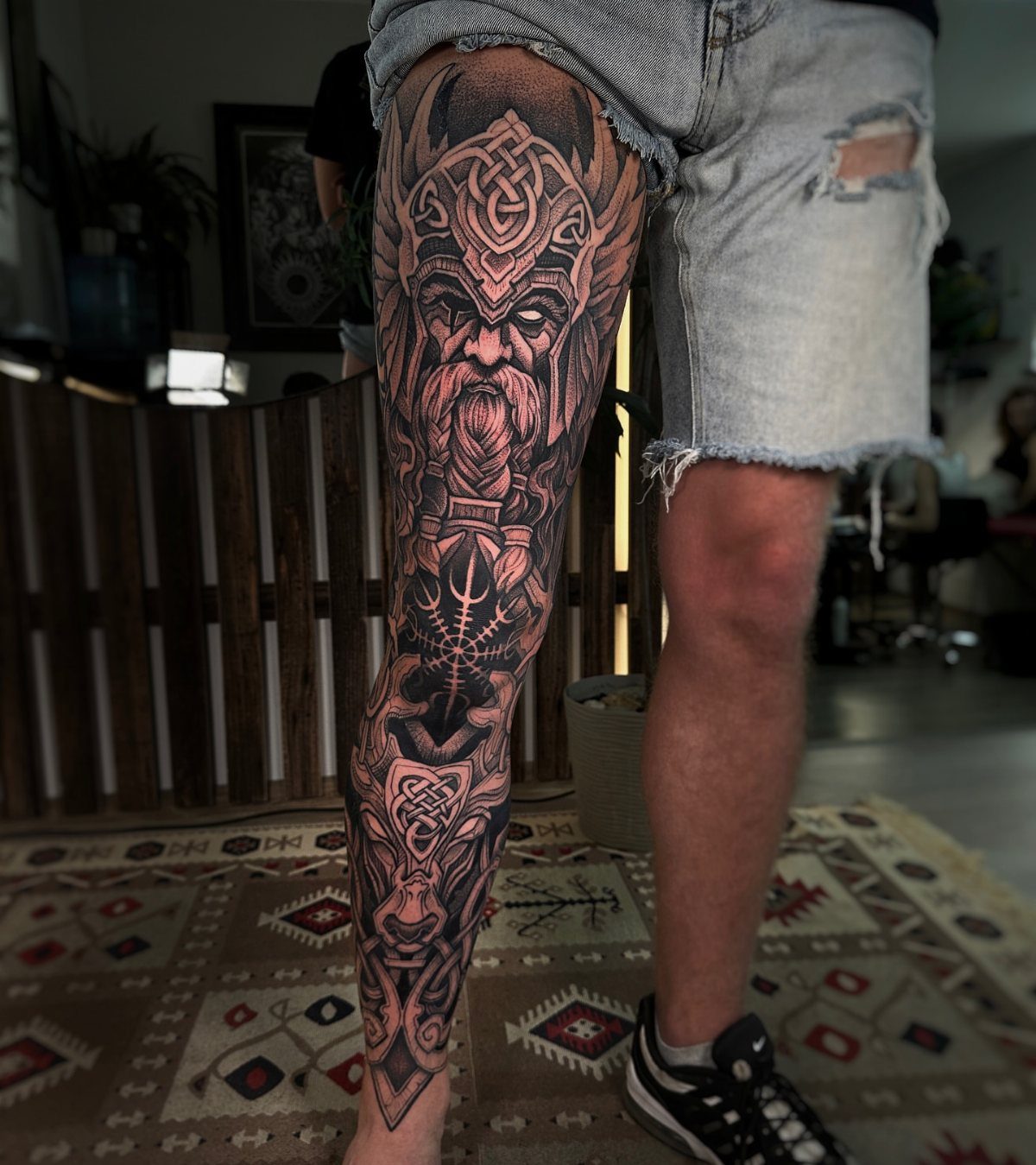Viking warrior tattoo with horned helmet on a man's calf and lower leg
