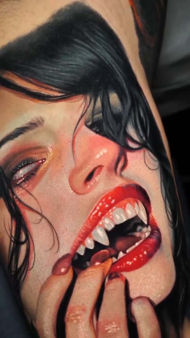 Vampire woman tattoo with red lips and fangs on a person's skin.