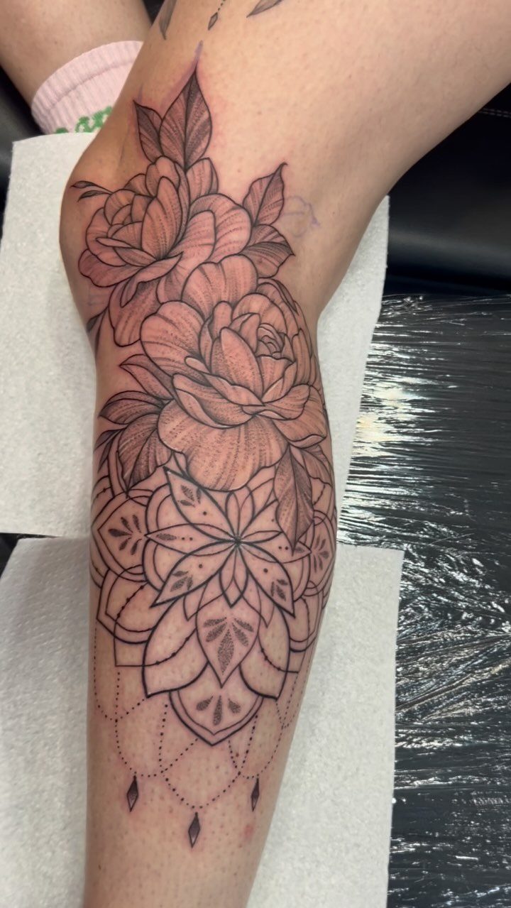 Lower leg tattoo featuring detailed roses above a symmetrical geometric mandala design.