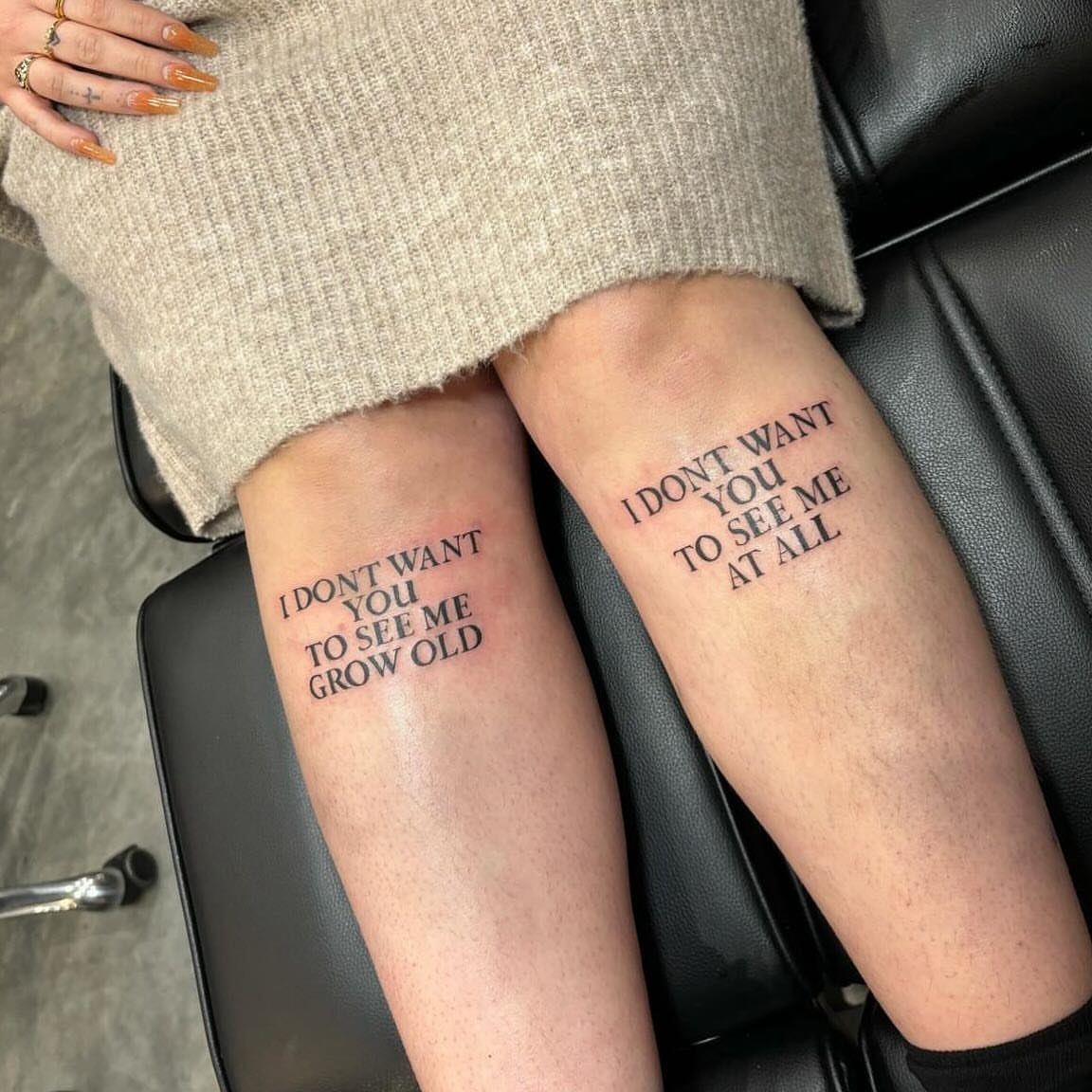 Calf tattoos with black text phrases on a person's lower legs.
