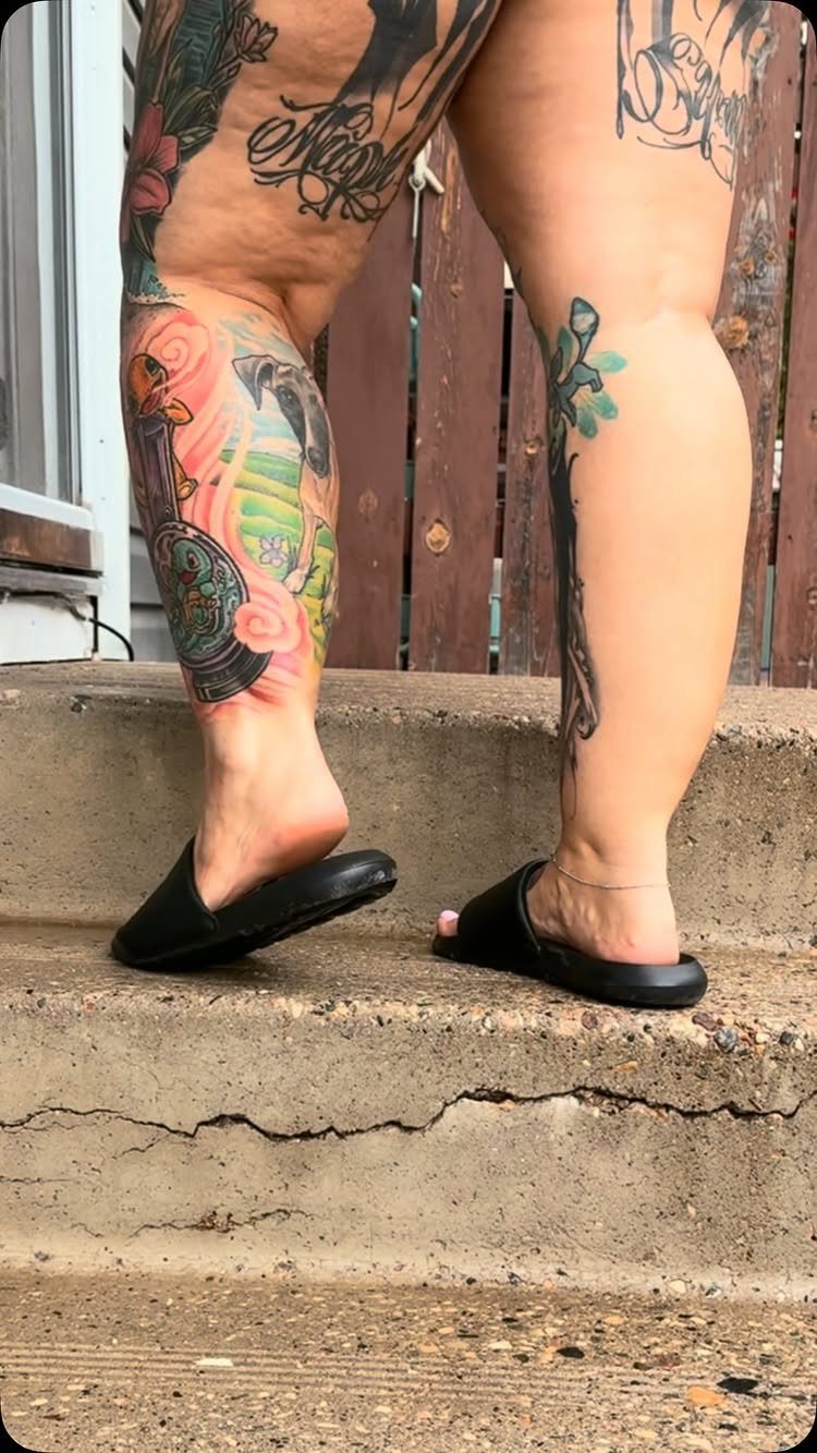 Colorful large scale tattoo on a person's calf standing on concrete steps.