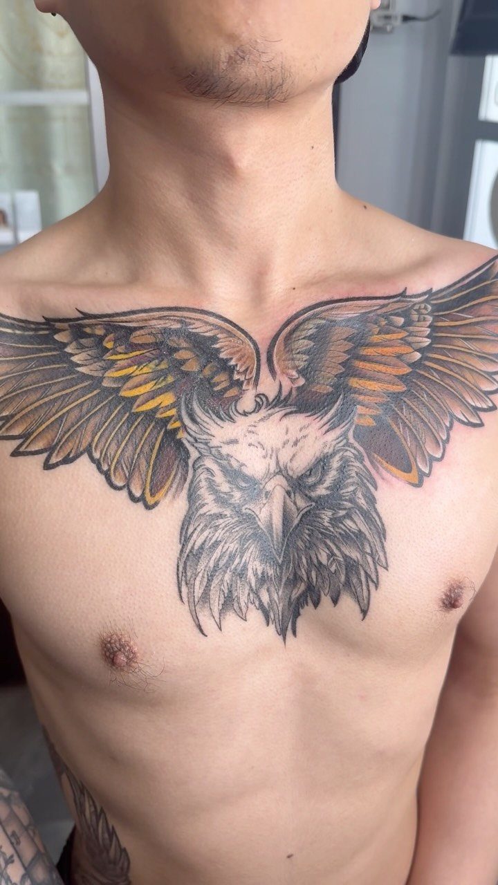Eagle tattoo with spread wings and detailed head covering a man's chest.