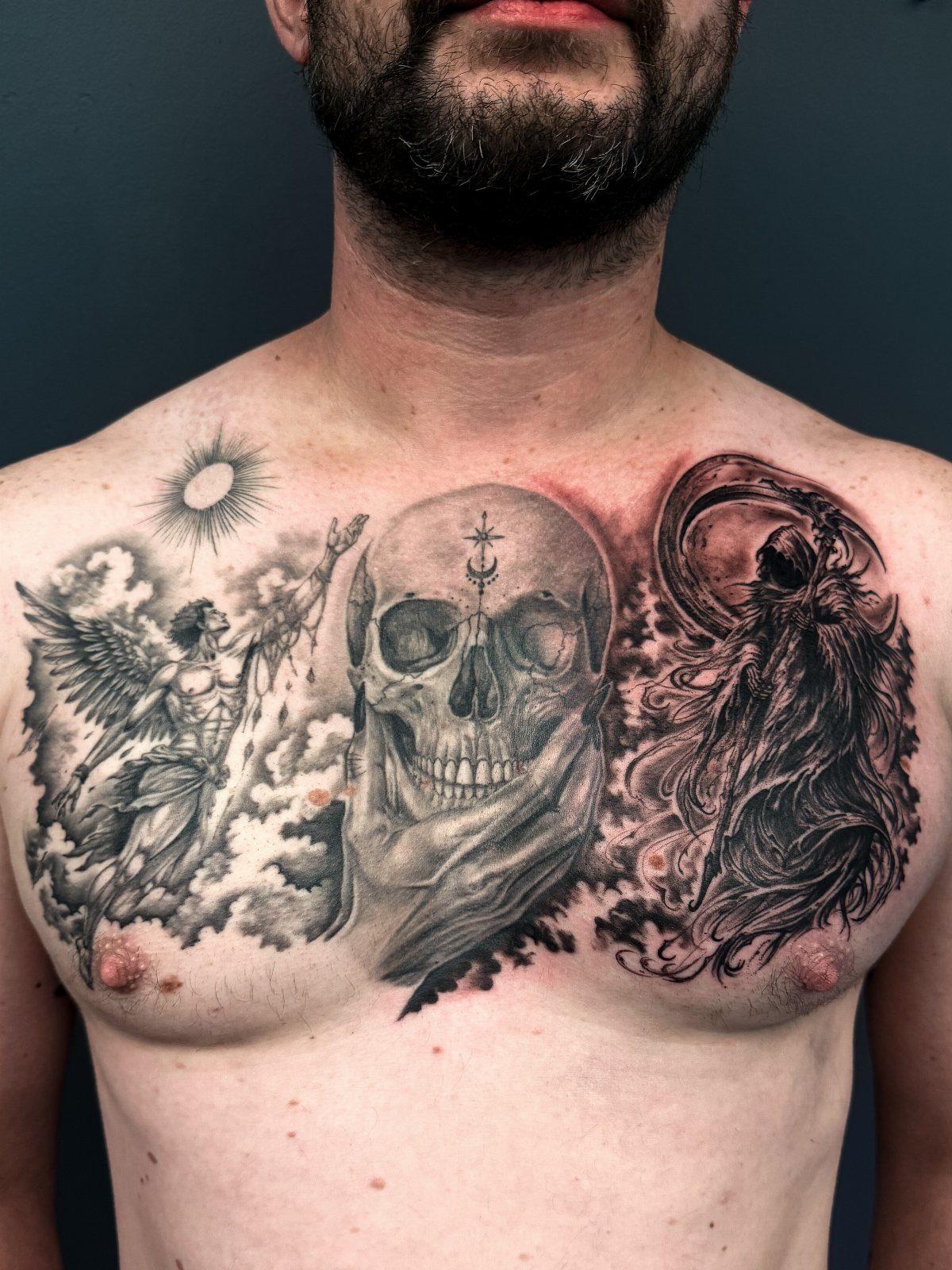 Chest tattoo featuring an angel, a central skull, and the grim reaper.