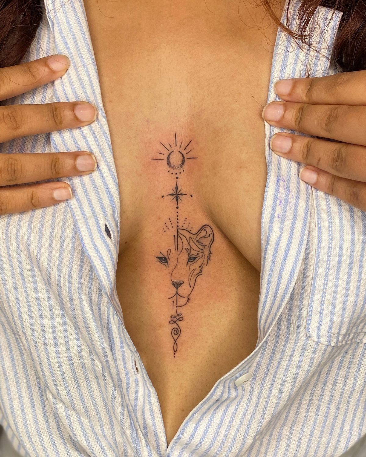 Sternum tattoo with a lion, sun, and moon on a person's chest