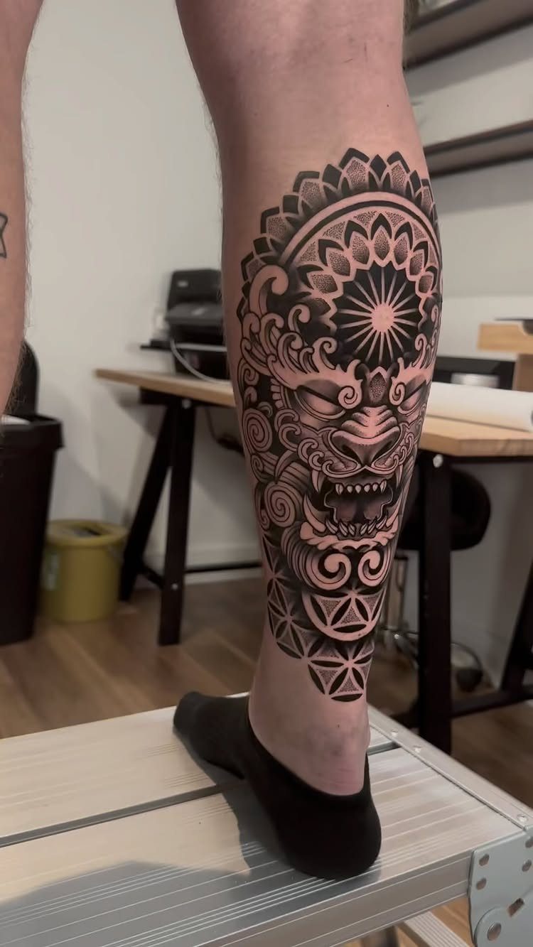 Intricate geometric blackwork tattoo of a tiger face on a man's lower leg.
