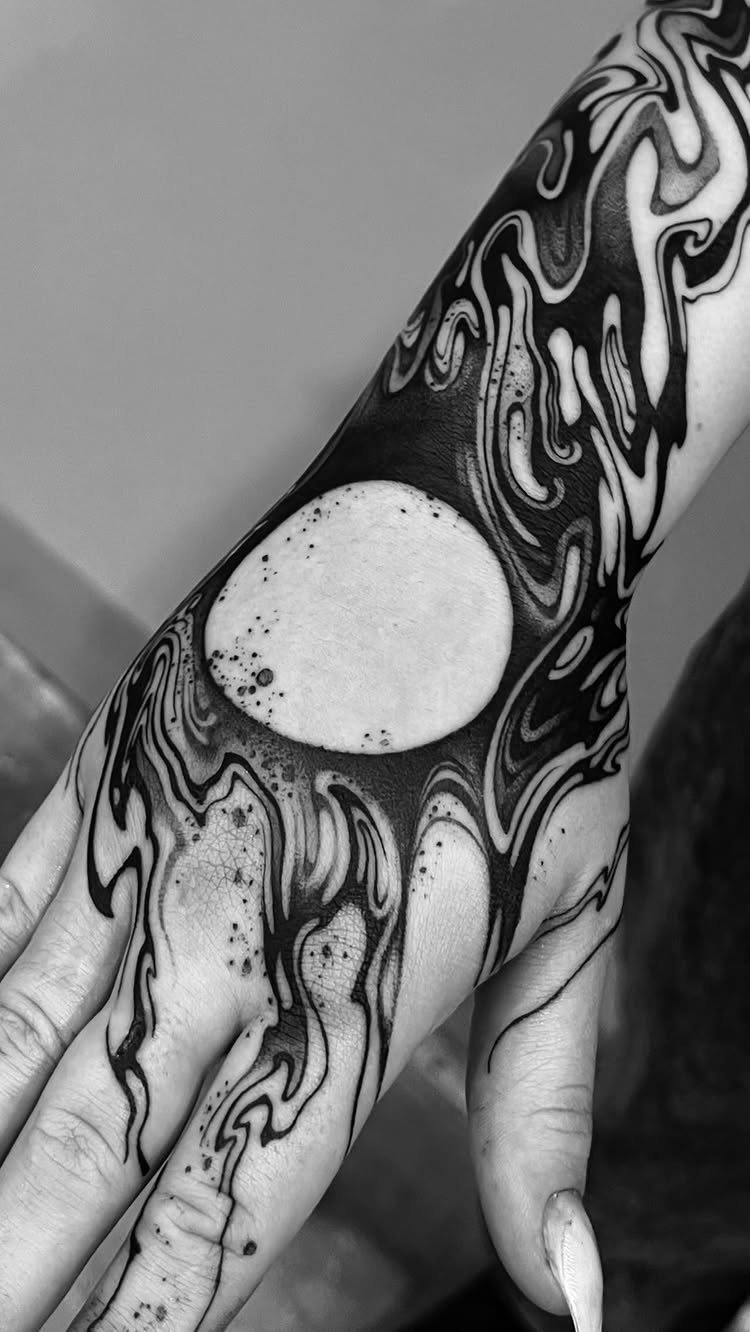 Intricate blackwork tattoo with swirling patterns covering a hand and forearm
