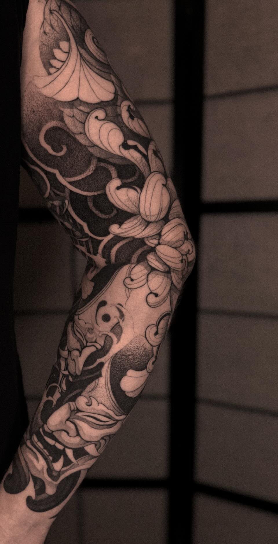 Full sleeve Japanese blackwork tattoo on an arm with floral and wave patterns