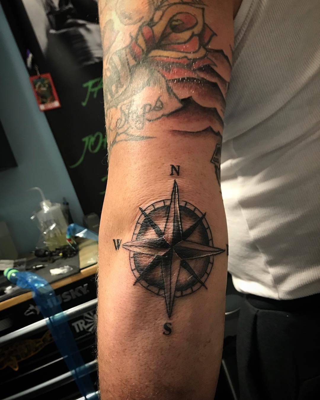 Compass rose tattoo with cardinal directions on a person's forearm