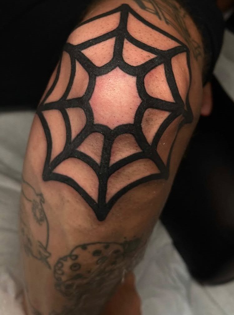 Spider web tattoo centered on a person's elbow with bold black ink lines.
