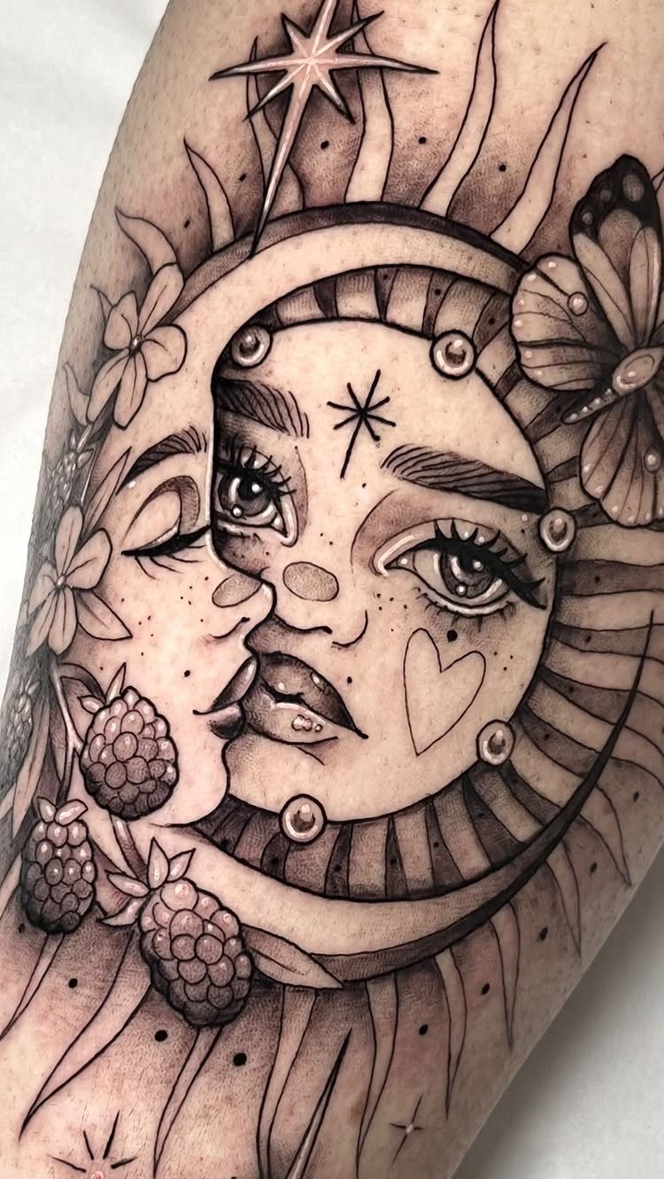 Sun and moon face tattoo with berries and a butterfly on skin.