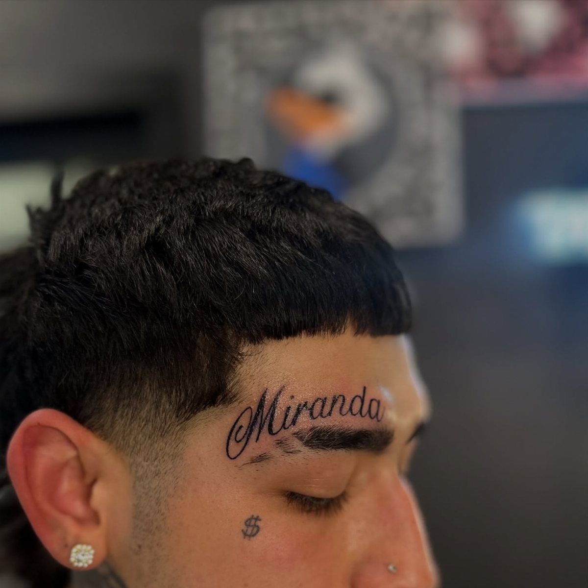 Man with a script tattoo reading Miranda on his forehead above the eyebrow.
