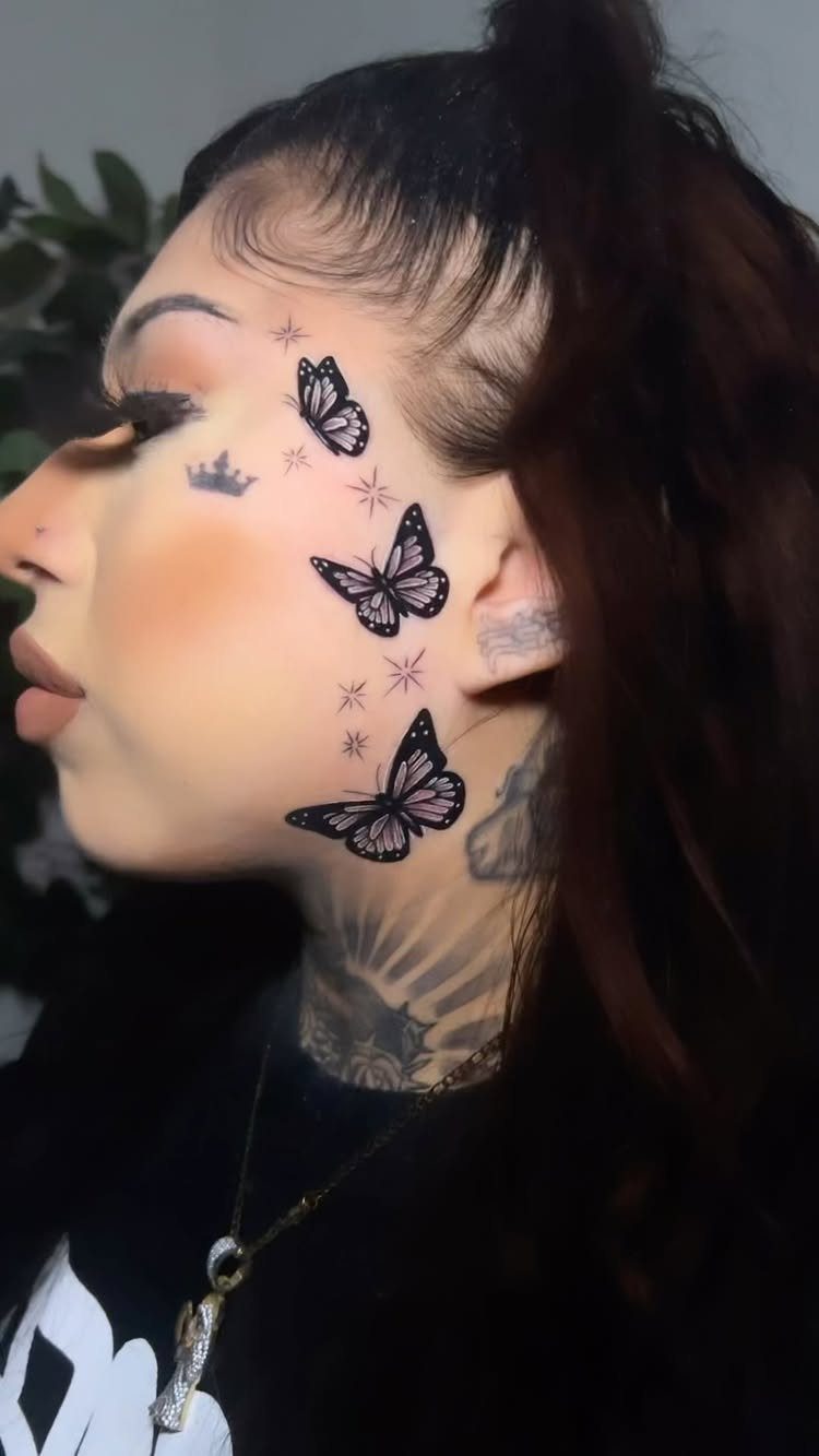 Woman with butterfly and crown tattoos on her cheek and neck in profile