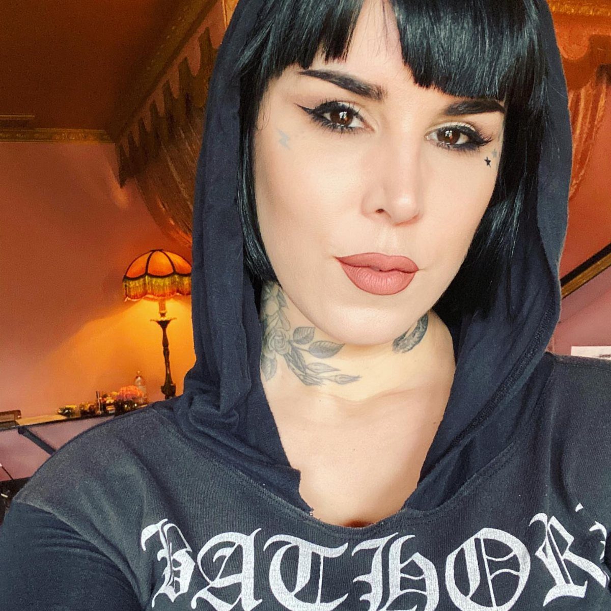 Woman with small star tattoos under her eyes and floral neck tattoos.