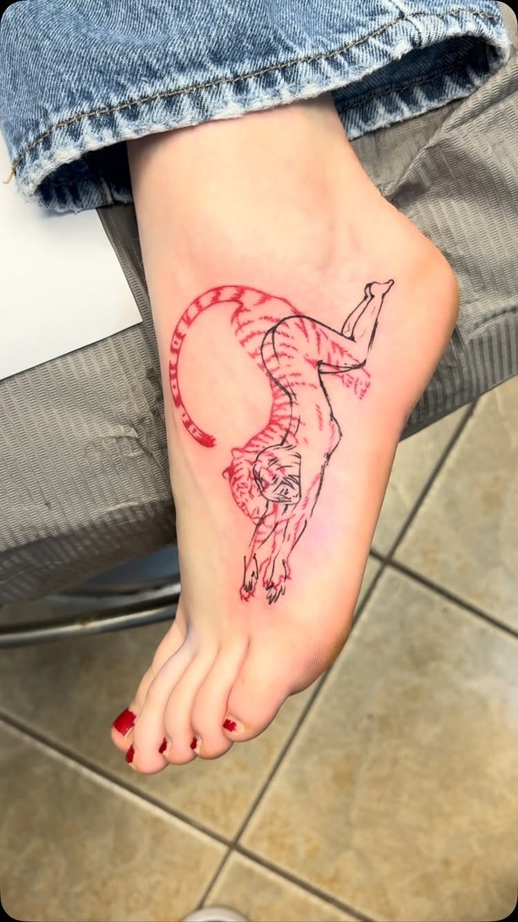 Animal tattoo on the top of a foot with red and black ink