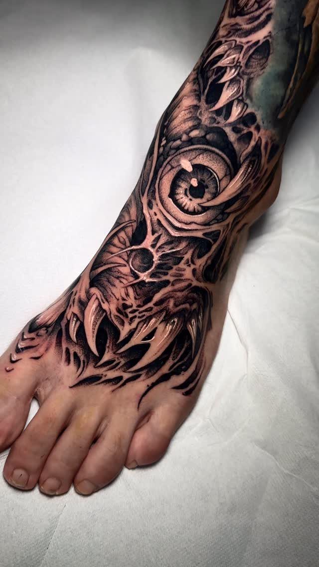 Foot and ankle with a detailed black and grey tattoo of a large eye.