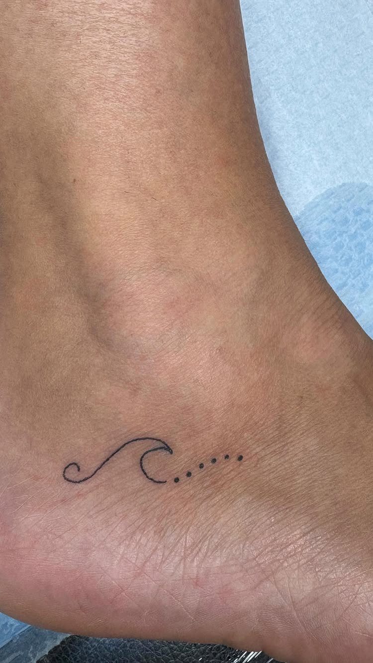 Small black ink wave tattoo with dots on the side of a foot.