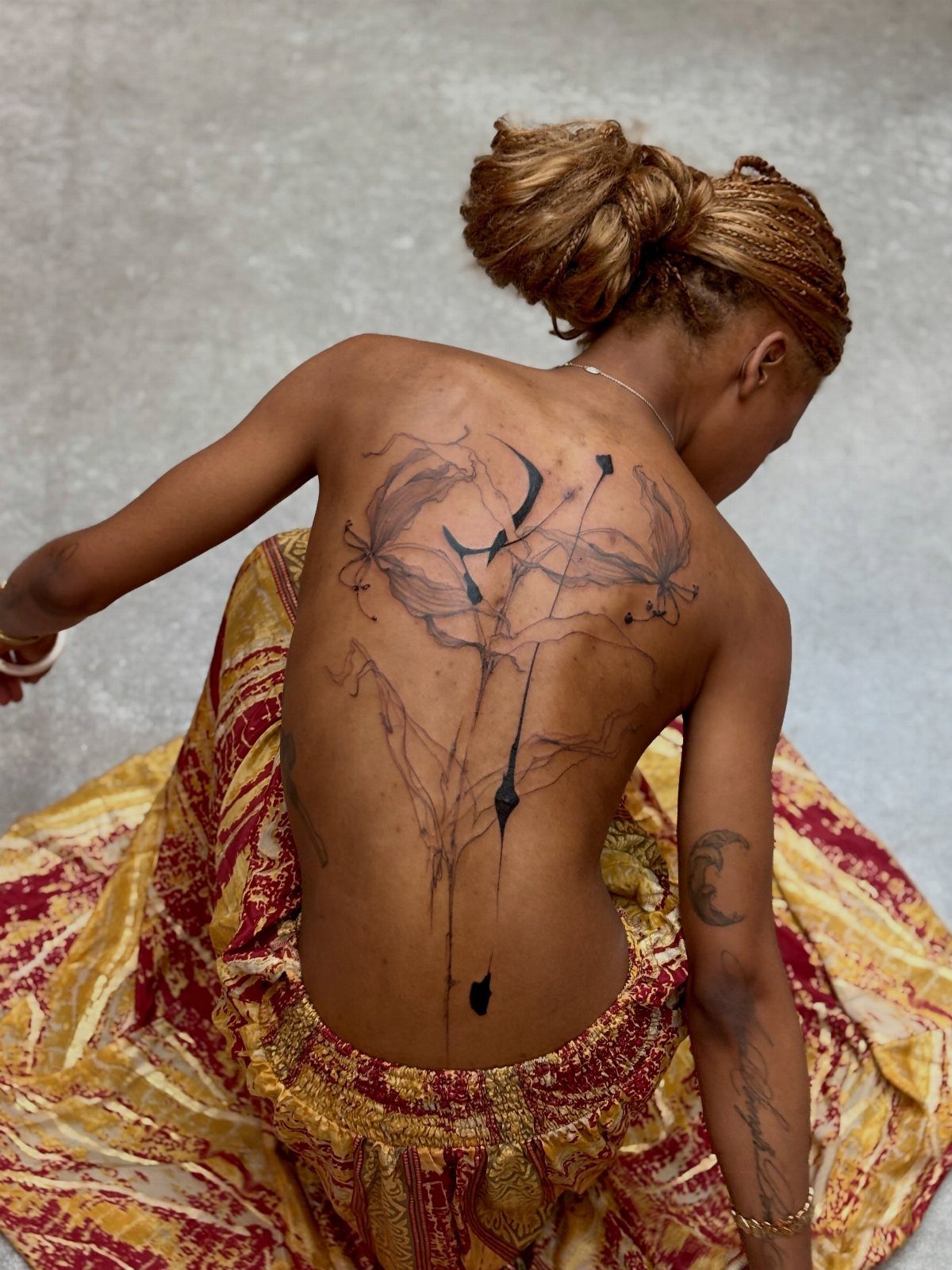 Woman with a large black abstract ink tattoo covering her entire back.