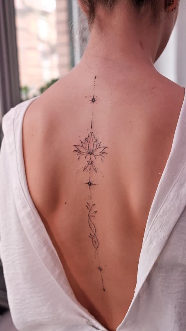Lotus flower and vine tattoo running vertically down a woman's spine