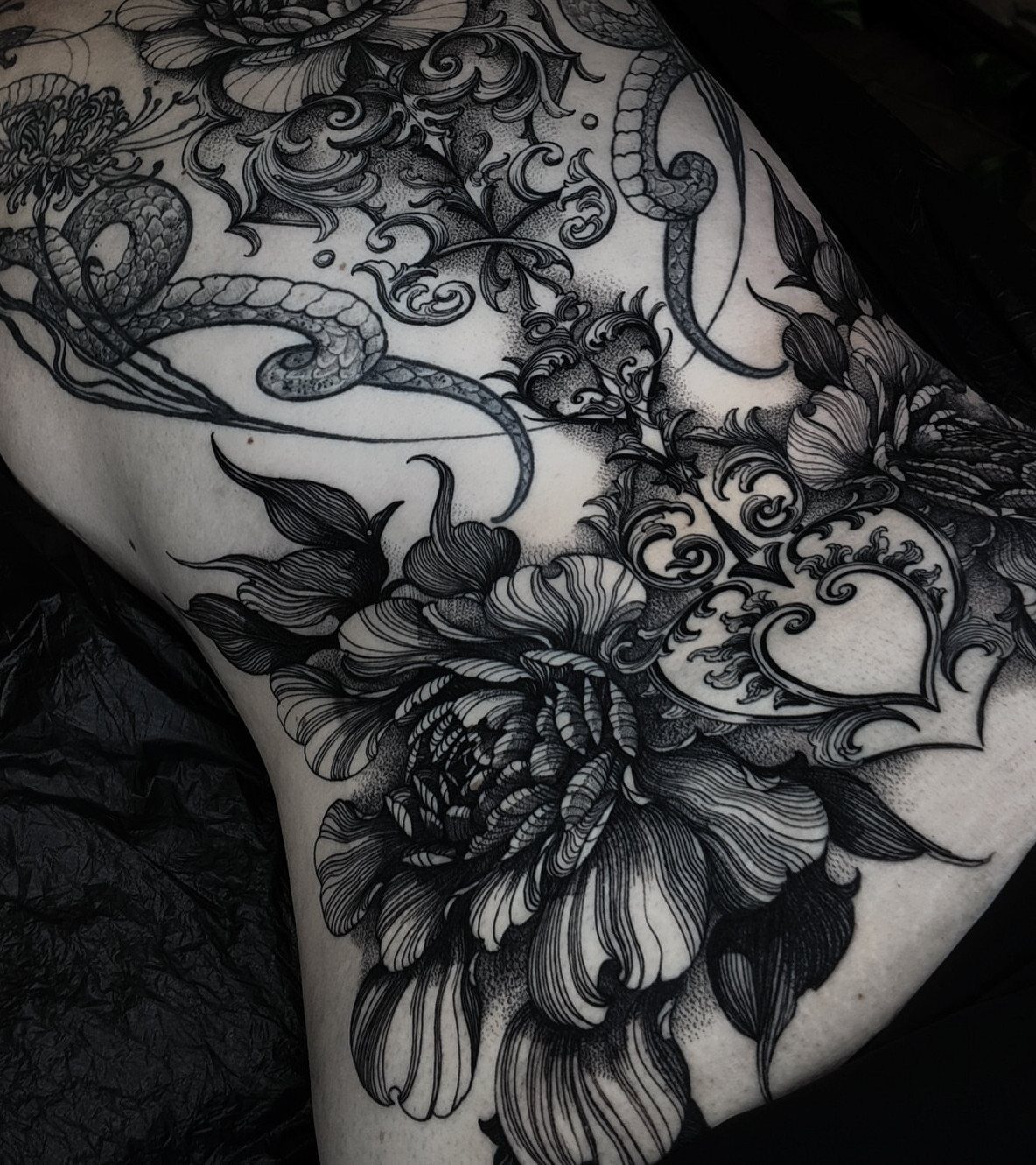 Detailed black and gray vintage pattern tattoo with peony and serpent on a back