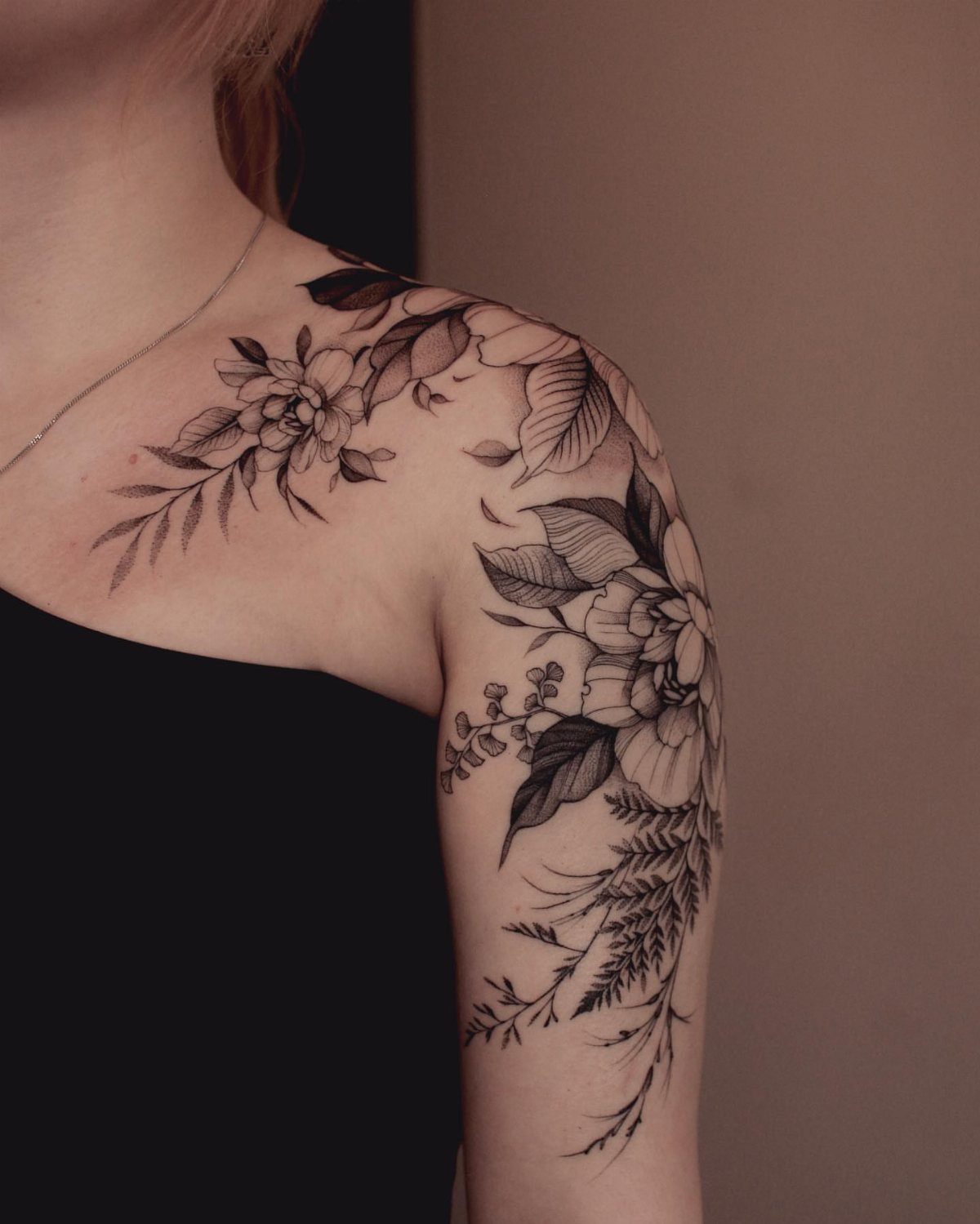 Floral cluster tattoo in bold black ink on a person's shoulder and upper arm.